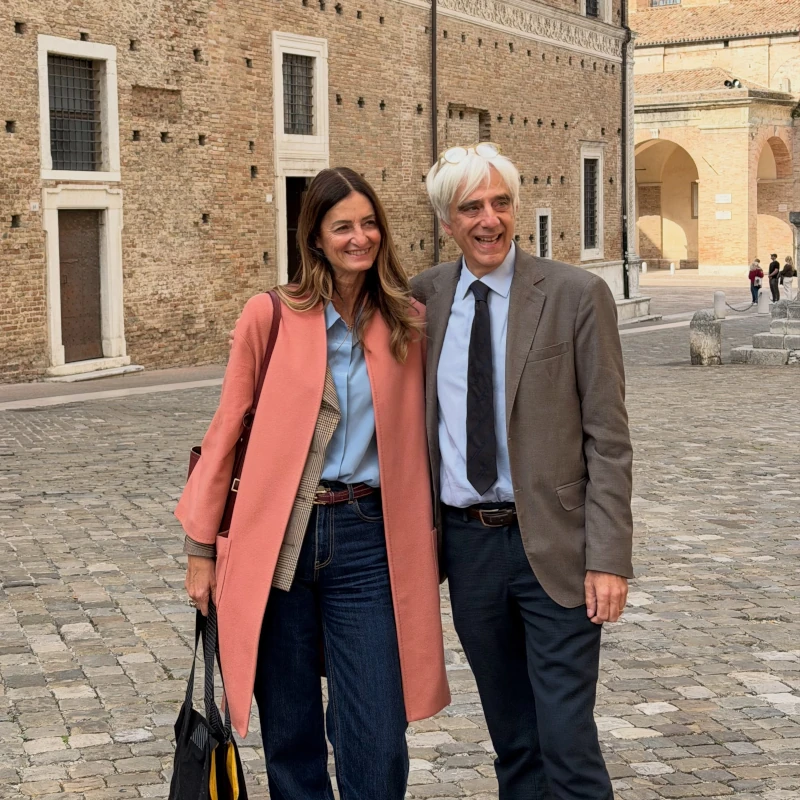 Marco Rocchi e Berta Martini sorridenti in piazza, a Urbino, davanti al Palazzo Ducale